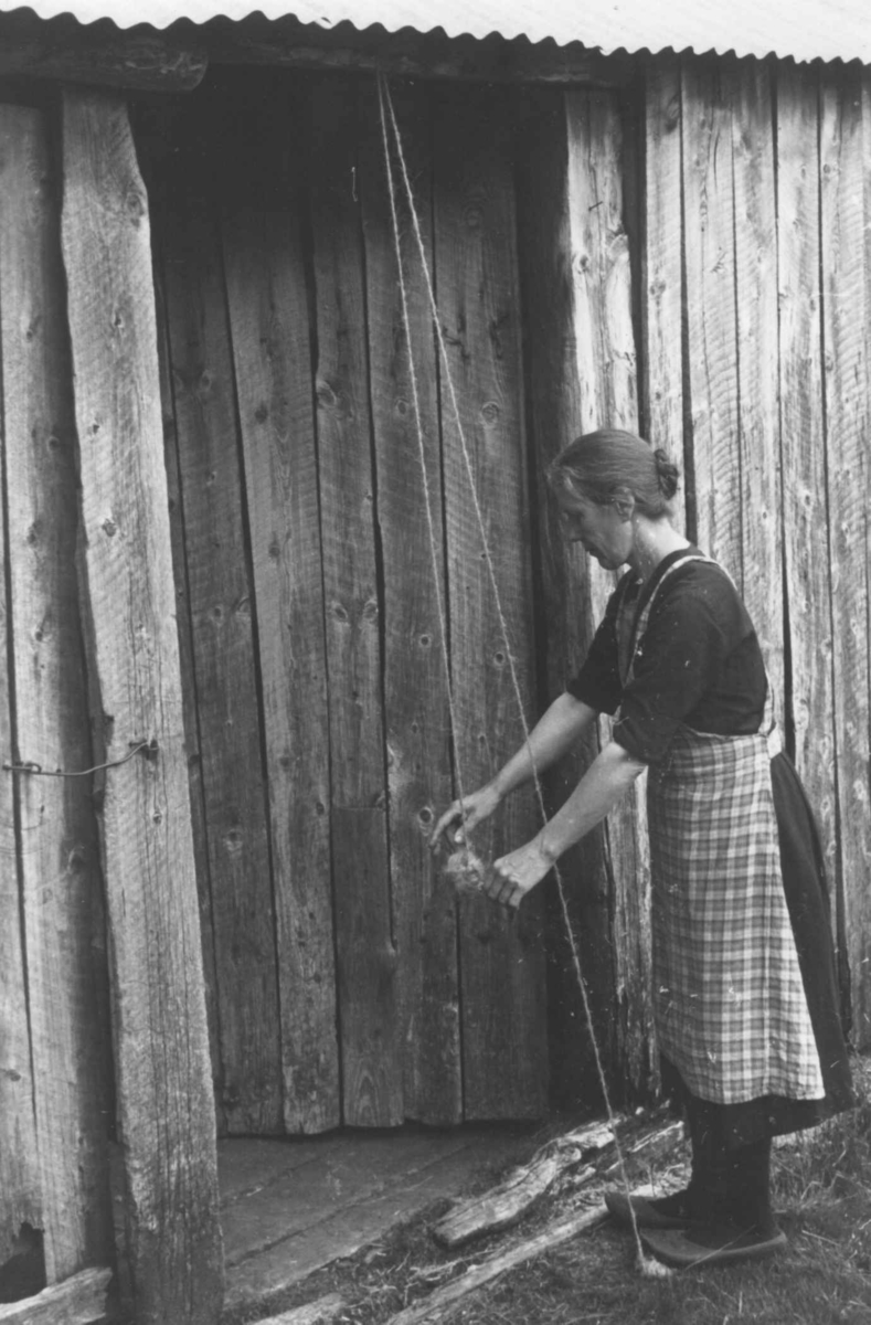 Gunhild Smeland tvinner lodde-garn. Åseral, Vest-Agder 1943.