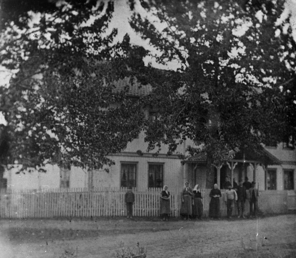 Råholdt, Eidsvoll, Akershus før 1800. Hovedbygningen. Husbondsfolket står på verandaen og tjenerne utenfor gjerdet.