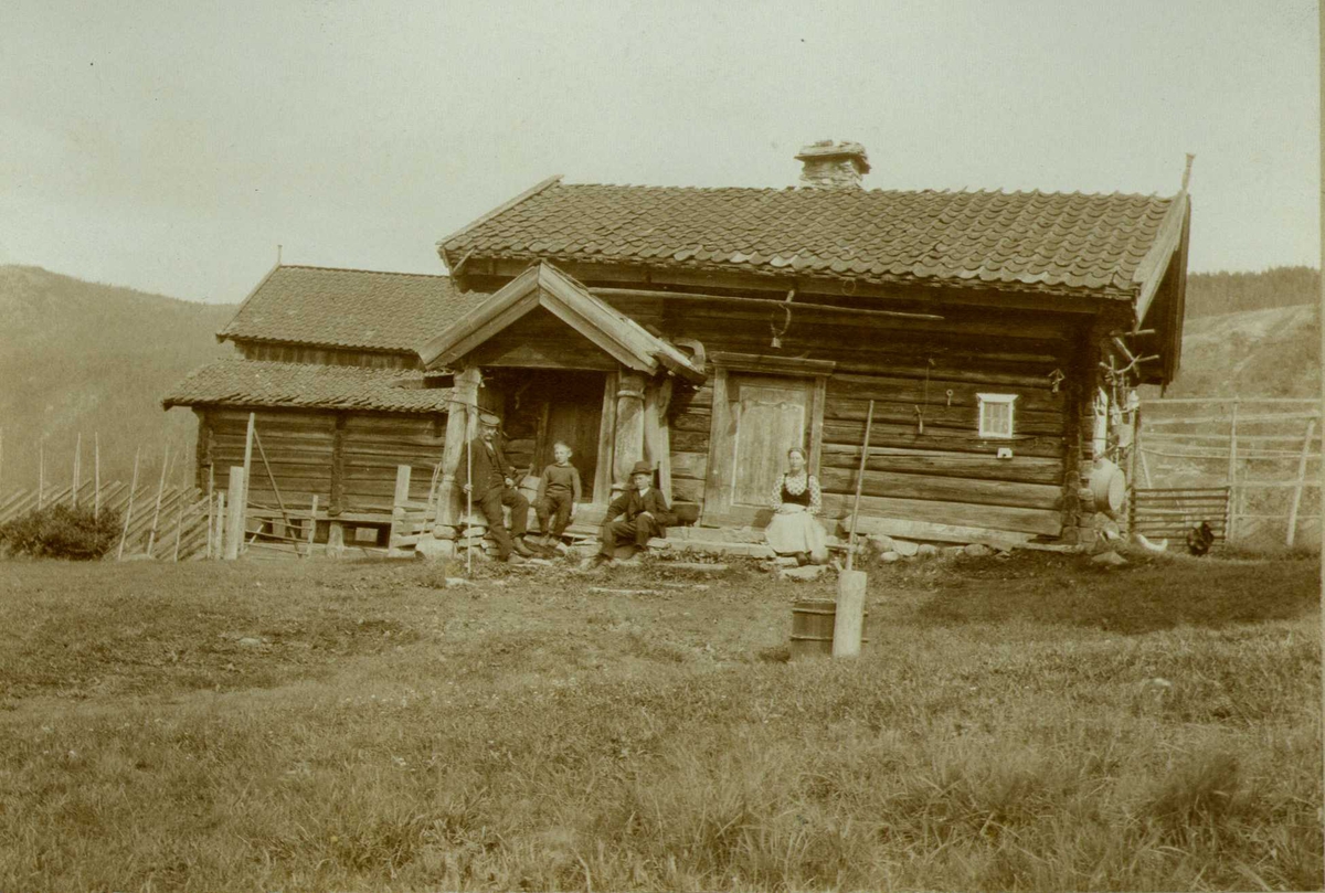 Gamlestuen, Nisi, Gransherad, Notodden, Telemark. Familie sittende foran huset. Fotografert 1907. 