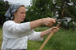 Fra slåttonna i juni 2005.Vert i drakt, sliper ljåen.