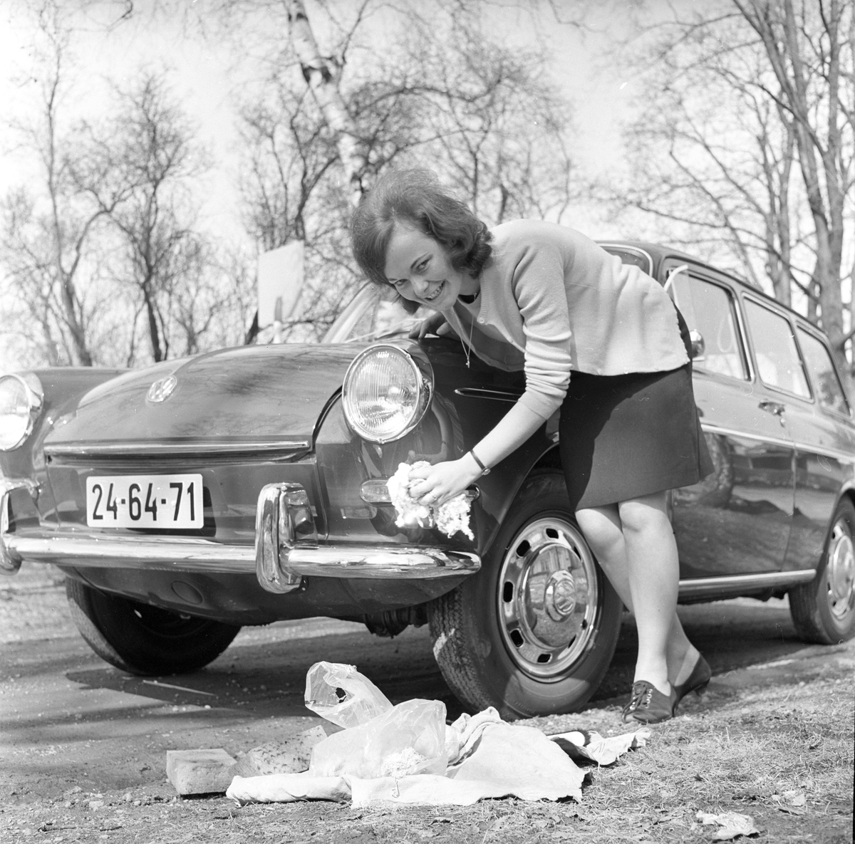 Vårpuss på bilen, dame vasker og steller bil. Fotografert 30. april 1966.