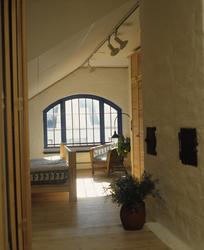 Soverom med buet vindu i utbygd loft i  gammel bygård. llust