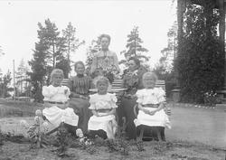 Gruppeportrett, seks kvinner i et hageanlegg. Tre ungjenter 