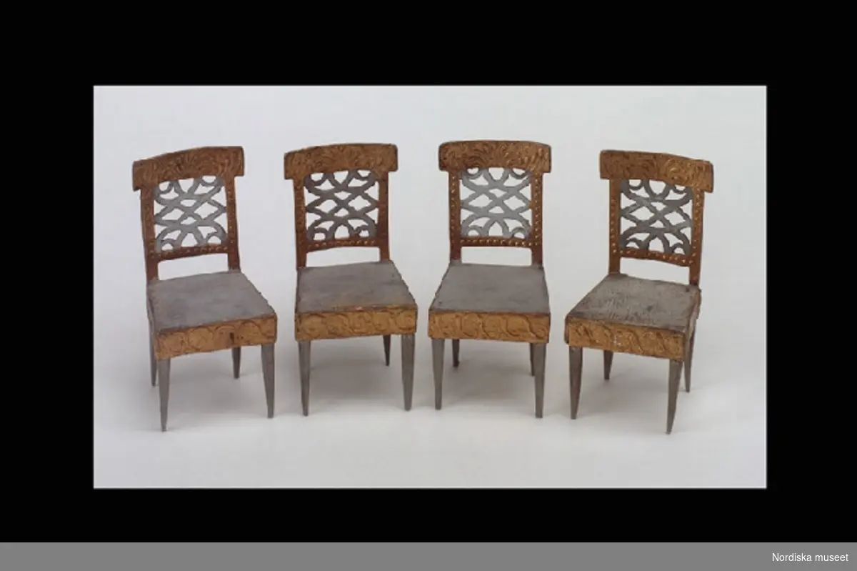 Inventering Sesam 1996-1999:
H 11,5 cm
4 st stolar till dockskåp tillverkade av trä, papp och massa. Fyra rakt nedåt avsmalnande ben av trä, fyrkantig gråmålad sits, sarg och fyrkantigt genombrutet ryggstöd av papp och massa med reliefmönster i guld och vitt.
Hör till dockskåp 165.280
Bilaga
Leif Wallin 1996