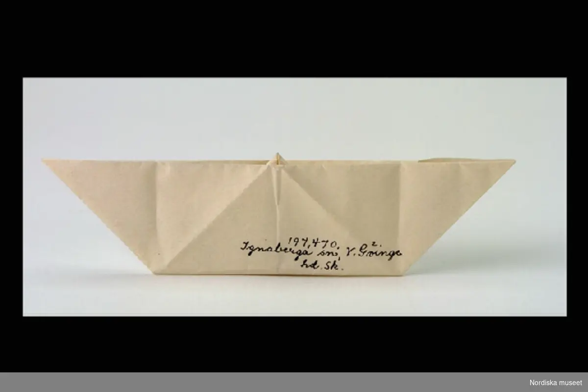 Inventering Sesam 1996-1999:
L 12,5  H 3,5 (cm)
Pappersvikning av vitt papper föreställande "Käringen i båten".
Birgitta Martinius 1996