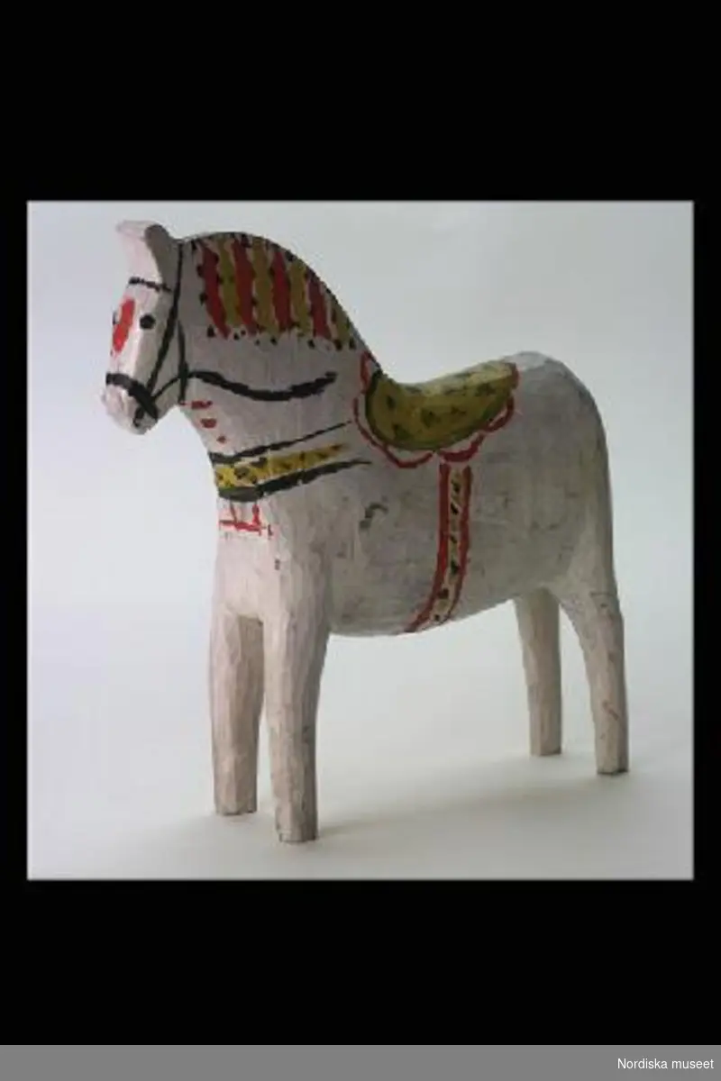 Inventering Sesam 1996-1999:
L 18  H 18,4  cm
Häst, dalahäst av trä, vitmålad med krusning i gult och svart.
/Birgitta Martinius 1996