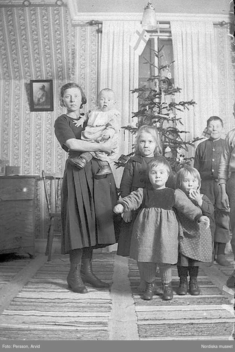 Gruppbild av en ung kvinna och hennes barn i hemmet. Sörsjön, Transtrand sn, Dalarna.