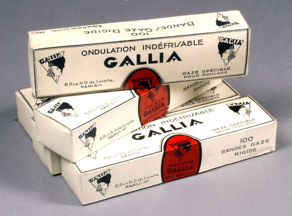 Fem pappaskar, vita med svart text: ONDULATION INDÉFRISABLE GALLIA. Innehåller stärkta gasbindor.