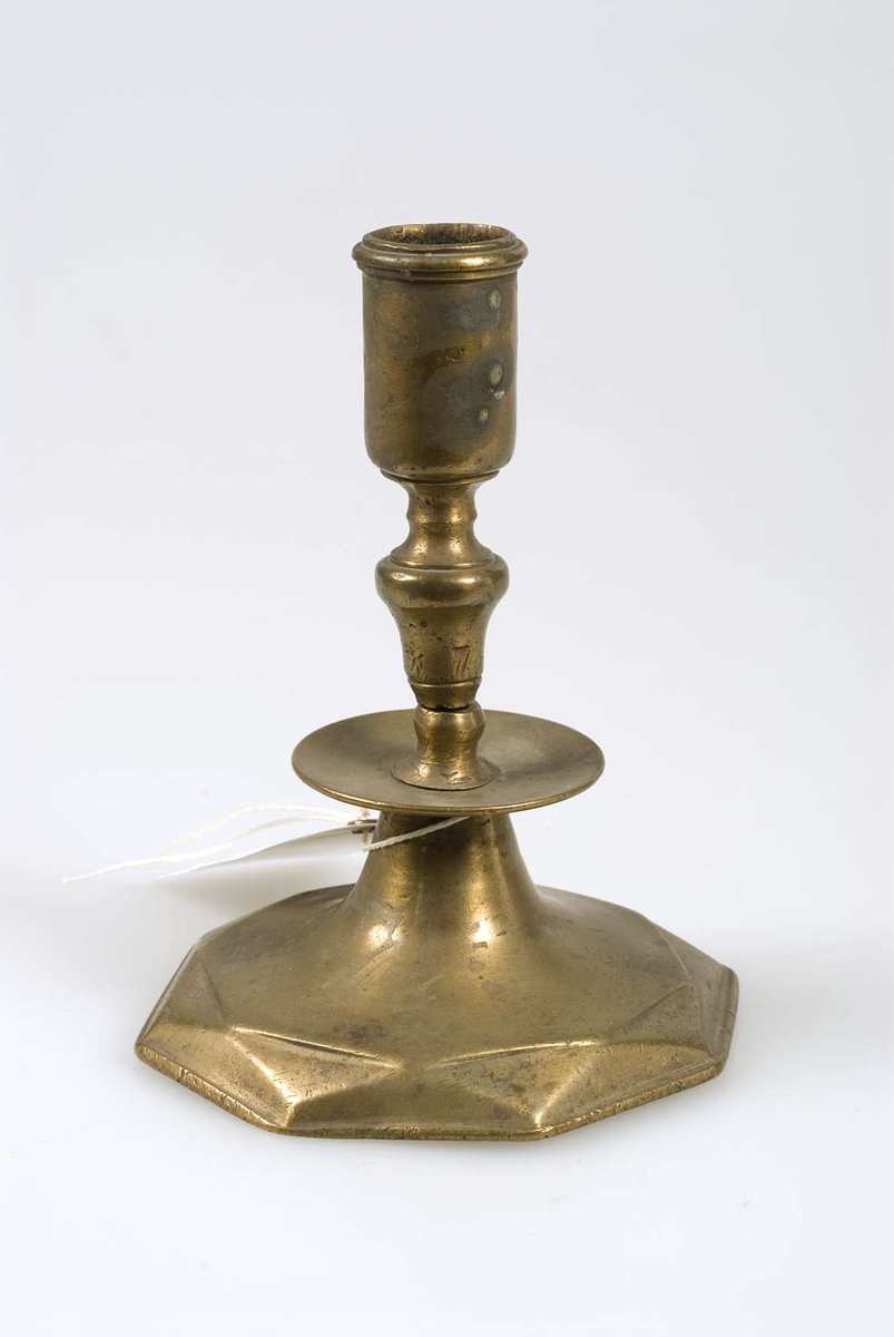 Ljusstake, enligt Museum Gustavianums katalog av malm, gjuten i tre delar. Ljusstaken är märkt "Vassunda 118 EC."