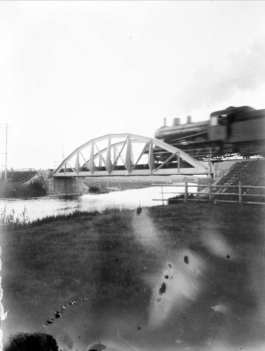 Järnvägsbro med ånglok, sannolikt över Tämnarån, Tierpstrakten, Uppland omkring 1915 - 1920