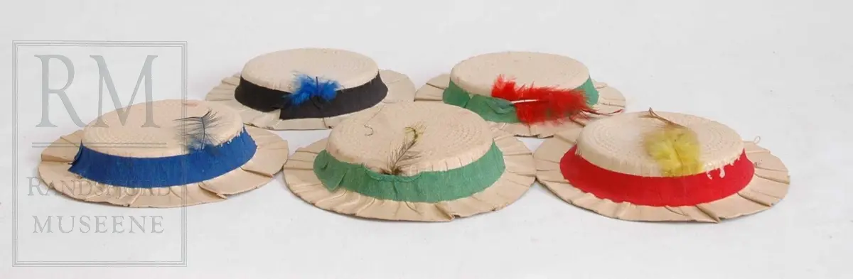 Flere ulike hatter og hodeplagg til bruk i utkledning og til festlige sammenkomster. Hovedsakelig kreppet papir, kartong og silkepapir. Se under "gruppering" for detaljer. 

Handelsvarer, flere maskinsydde og merket med Norsk ESH Oslo
