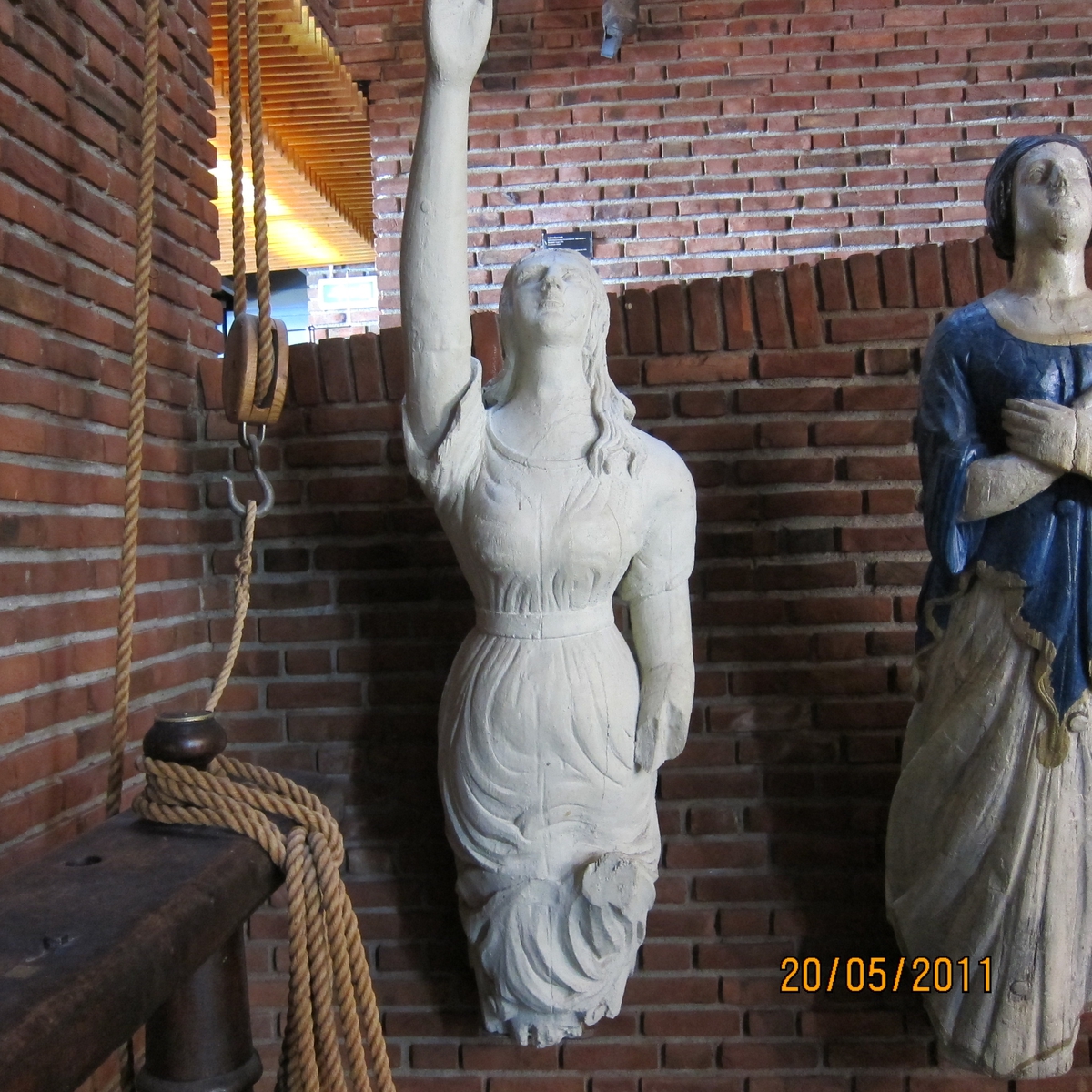 Kvinnefigur med høyre arm hevet, venstre underarm mangler.