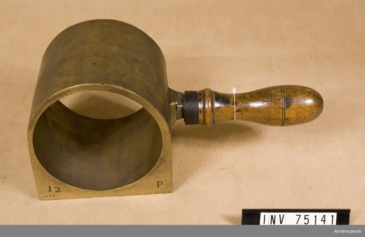 Grupp F:III(överstruket) V.
Schamplun av metall med handtag av trä för prövning av färdiga karduser, eller skott av 12.pund-ig kaliber.
