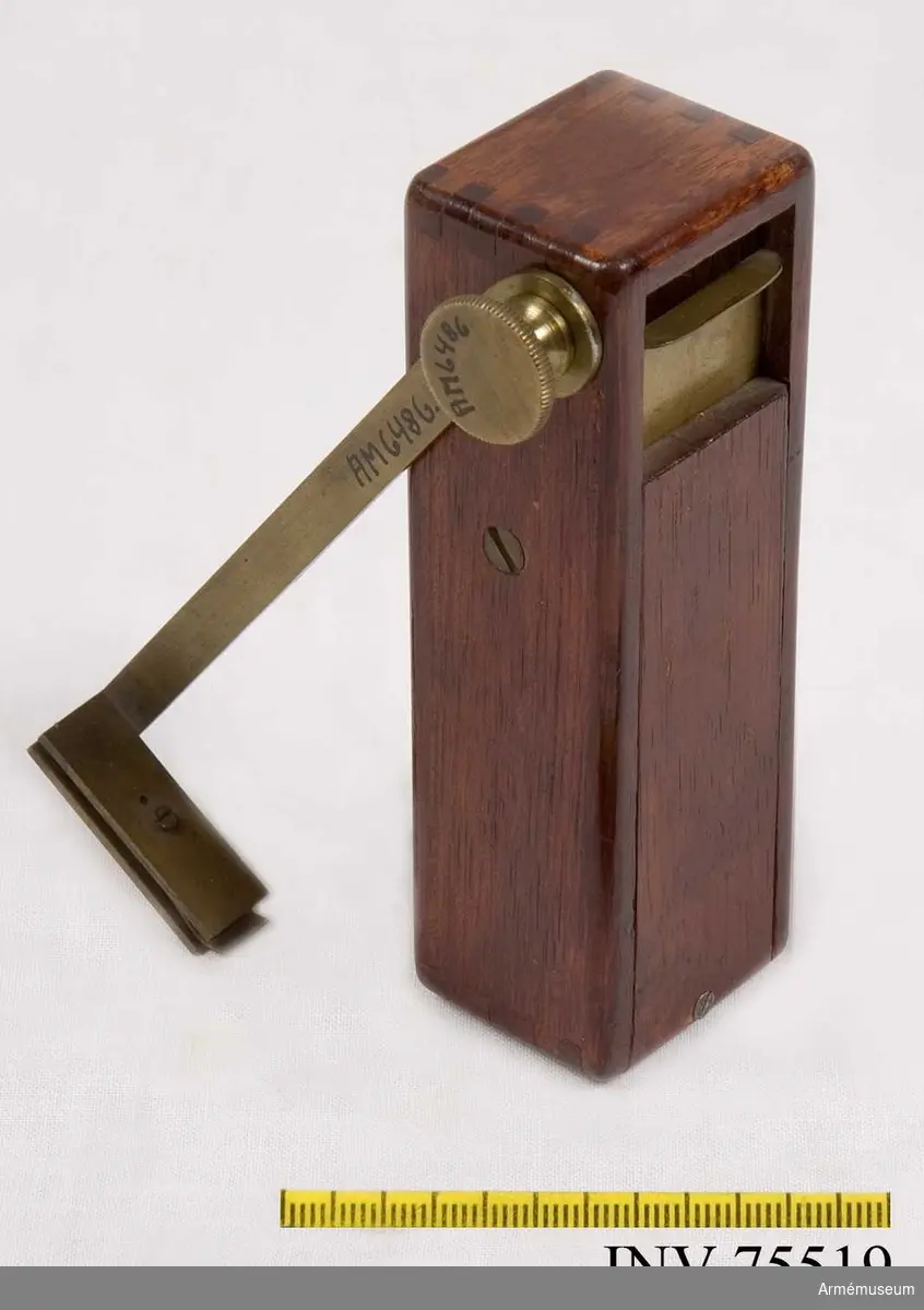 Grupp GII.
Konstruerat av Generalfälttygmästaren friherr Fabian Wrede ( f. 1802 + 1893), på 1850-talet.
I en rektangulär låda av mahogny upphängd spegel med pendelanordning. Lådan i nedre ändan försedd med hylsa för koniskt stativhuvud, i övre ändan dels en glasruta, dels, motstående ett skjutlock av messing med fastklämd, graderad pappersskala, skalan försedd med ett litet runt hål för sikte. Vid avläsning vrides skalan i 90 grader ut från lådan, varefter avläsning sker genom hålet i skalan med spegelbilden. När instrumentet icke användes, ligger skal-armen längs lådans kant. - Ett skruvhuvud saknas. Beskrivning: Egil Lönnberg. 