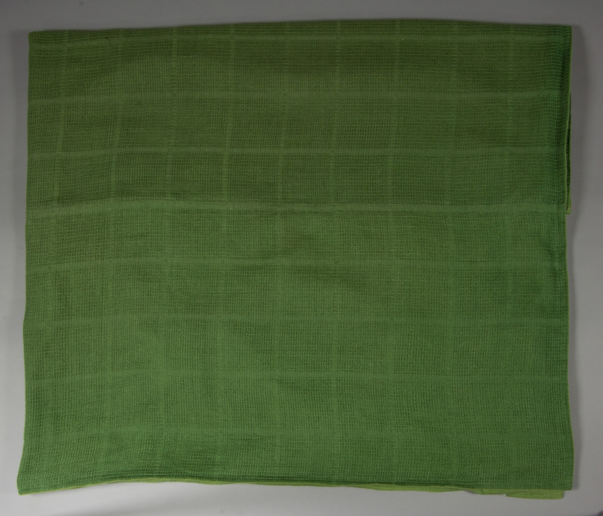 Överkast till säng. Tillverkat av handvävt linnetyg., mörkgrönt, vävt i stramaljbindning, myggtjäll med stora rutor. Två våder hopsydda på mitten, hörnen formade för att passa omstopp och nedhängande del fram. Sidorna, nedre kanten fram och den tänkta viklinjen för nerhänget kantade med gröna linneband. Överkastet är helfodrat med grönt linnetyg i tuskaft.