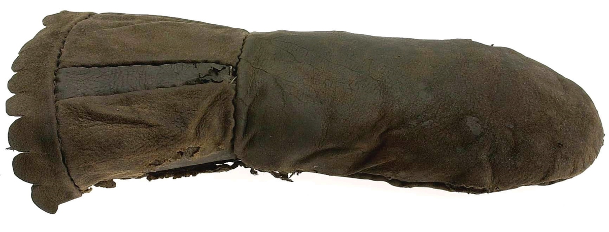 En kragvante till höger hand. Sydd av flera kraftiga läderstycken. Påsydd bård i ett stycke i form av rundade "tungor" längs kragkanten.