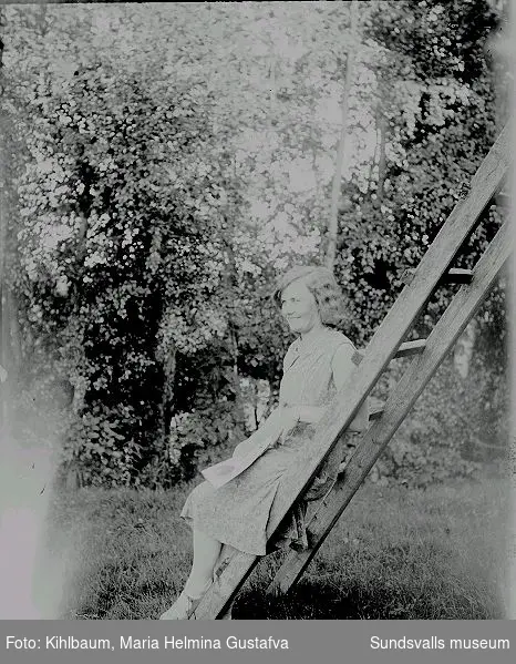 Kvinna sitter på en stege i utemiljö.