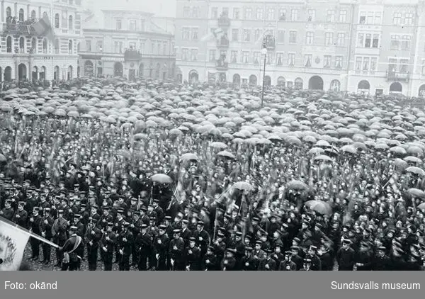 Folksamling med paraplyer på Stopra torget i Sundsvall. Troligen Gustav Adolfsdagen och unionsupplösning ("den rena fanan")