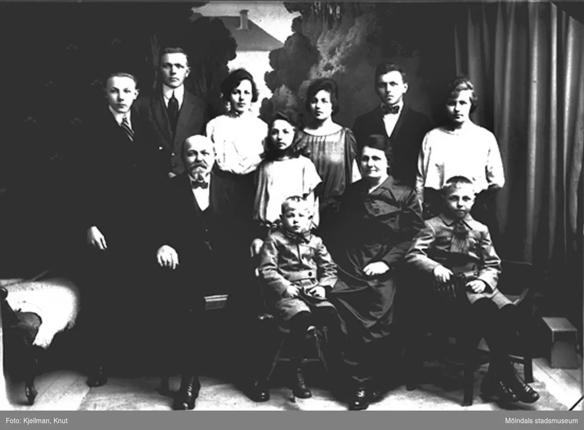 På baksidan finns en lapp påklistrad med texten: Mölndal, Glas, år 1915. Fotot föreställer August Persson, åkeriägare i Gårda (Göteborg), med familj.