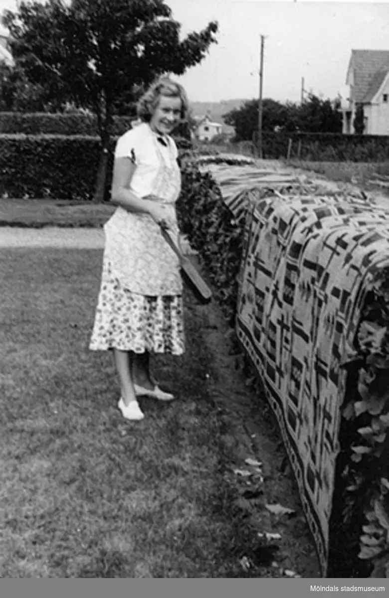 17-åriga Karin Friberg (gift Gustafsson) borstar av mattor, 1950. Troligtvis i Förslövsholm.