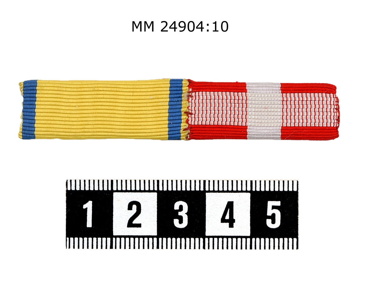Släpspänne av räfflat sidenband på rektangulär bricka. En del i lodrät randning blått, gult, blått, som står för kungliga svärdsorden. En del i färgerna rött och vitt, som är en dansk medalj (möjligen för räddning av drunknande). Fästnål på baksidan.