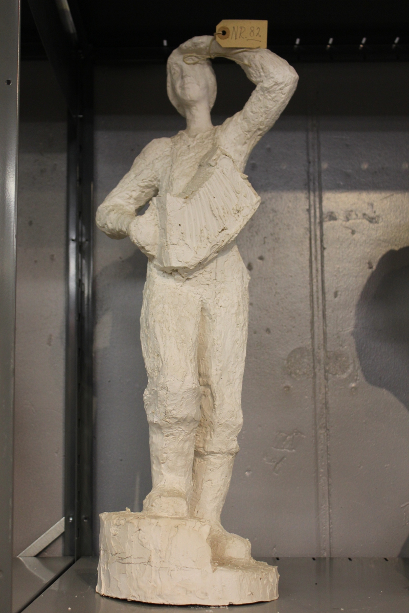 Skulptur i gips av en mann med trekkspill. Tittel: "Fisker med trekkspill". Utkast 1. Se også nr.070.