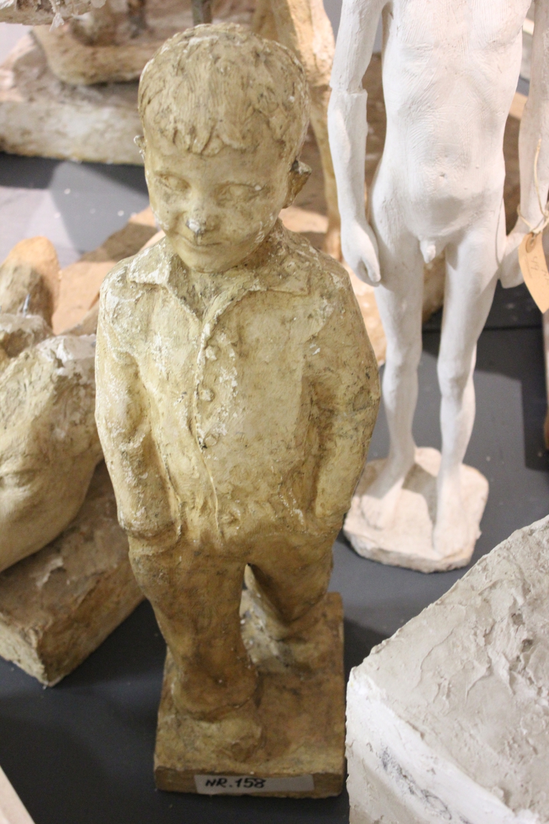 Skulptur i gips av en ung gutt med hendene i lommene. Tittel:  "Ka heite du då"?, "Vigelandsgutten"?