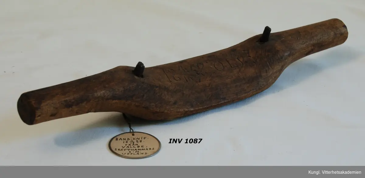 Bandkniv  bestående av träplatta med kniv å undersida
fr. Vällde Skäfthammar.