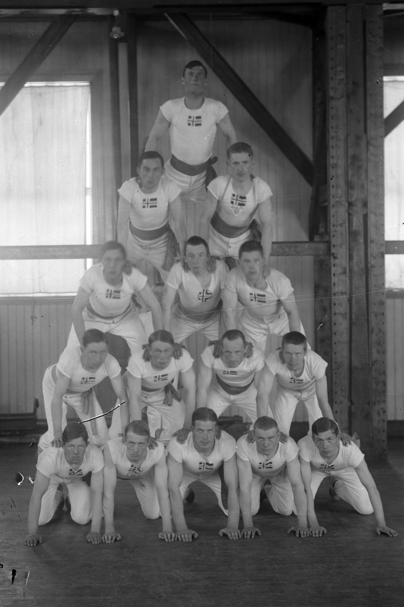 Gruppebilde av turnere i "pyramideformasjon", fotografert i gymsalen til BSIN.