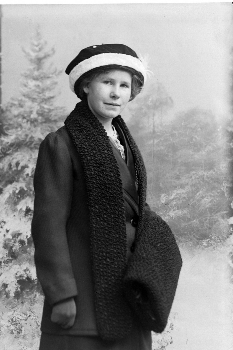Studioportrett av kvinne, iført vinterklær og foran et bakteppe med vintermotiv.