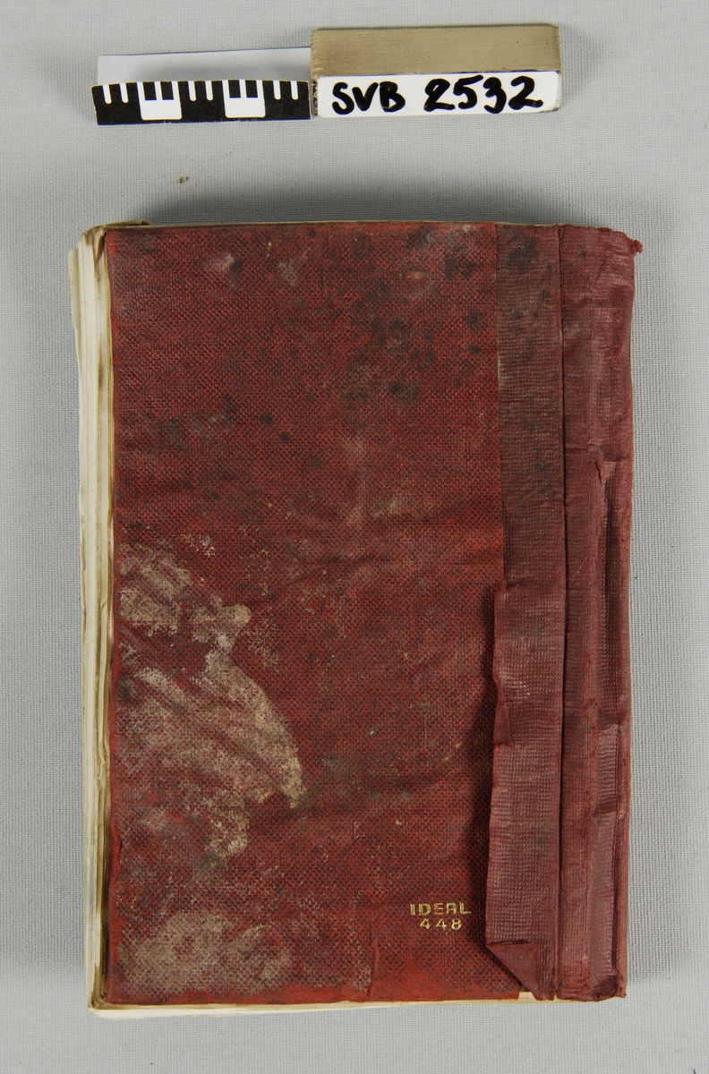 Linjert notatbok med omslag og rygg av rødt papir. Ryggen har løsnet
