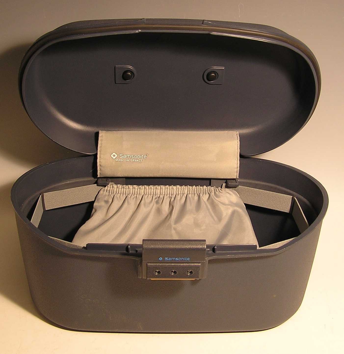 Form: ovalformet korpus med lokk , kodelås, innvendig lomme, håndtak
