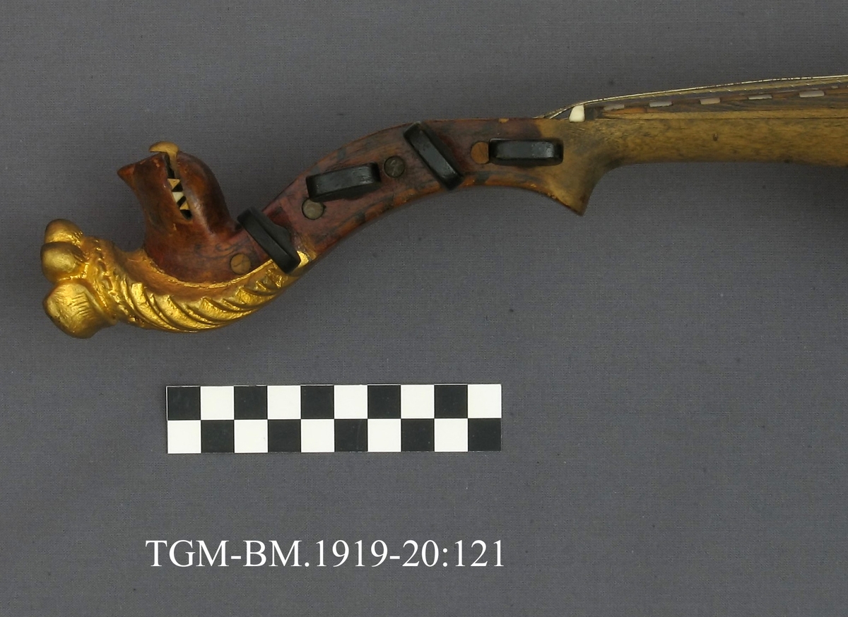 Fra protokollen: Hardingfele av den eldre, smale typen. Bruleggjingi stjerneforma, raud ferniss, stillepinnar og hovud spm vane (Hovudet nygylt). Paa merklappen inni stend: Fabrikeret af Erik Johnsen Helland i Bøe 1838. (Aarstalet ber merke av aa vera retta, serleg seinste siffer; papiret under aarstalet er vekkskrapa og talet uppnya paa berre treet.). Lok av gran, trojsk av hegg, botn av svartor, hovud av bjørk.