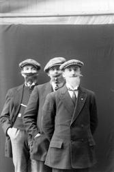 Studioportrett av tre menn med falske skjegg og sixpence.