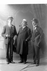 Studioportrett av tre menn i helfigur.