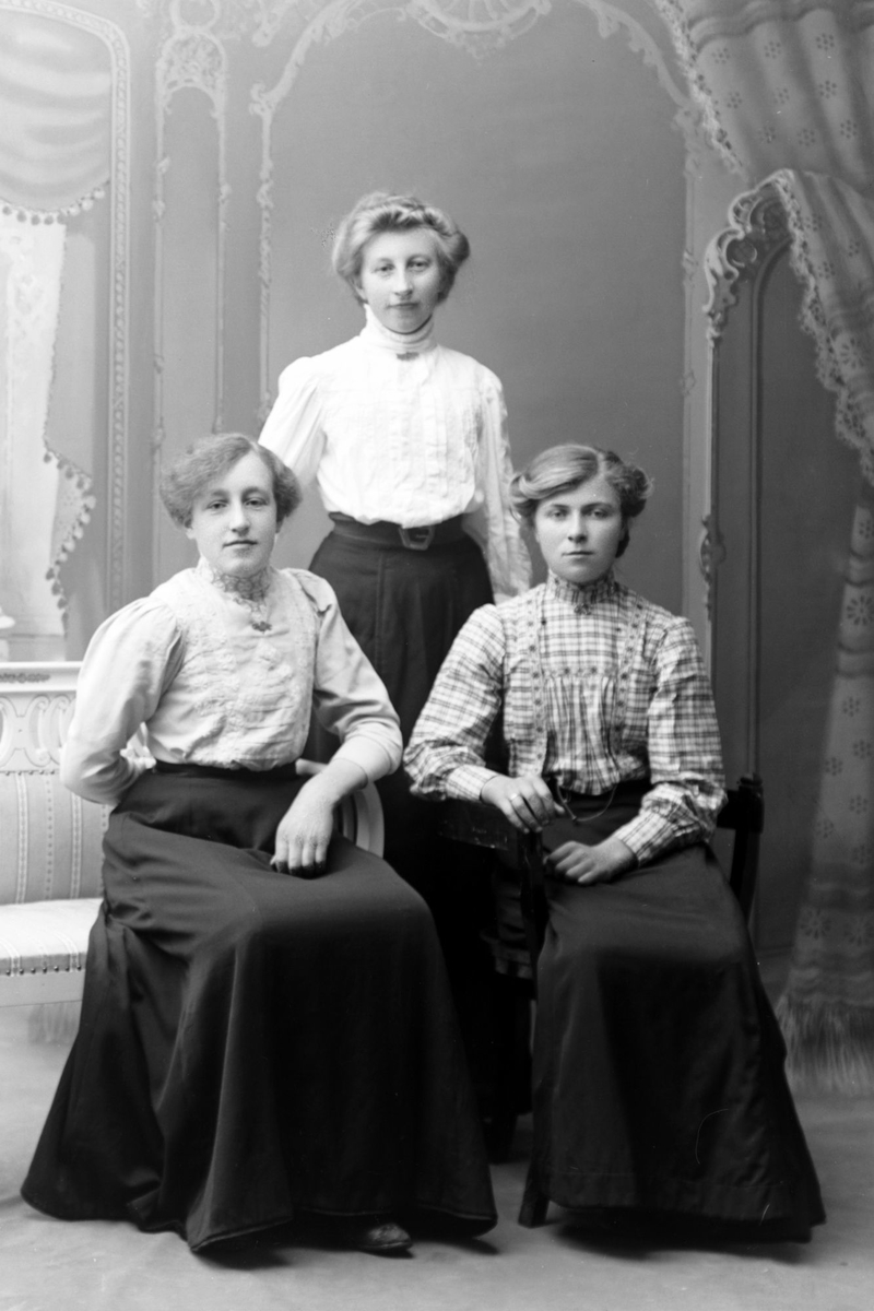 Studioportrett av tre kvinner i helfigur.