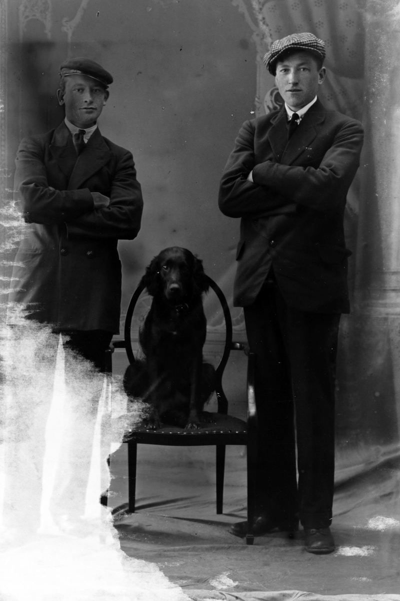 Studioportrett av to menn og en hund.
