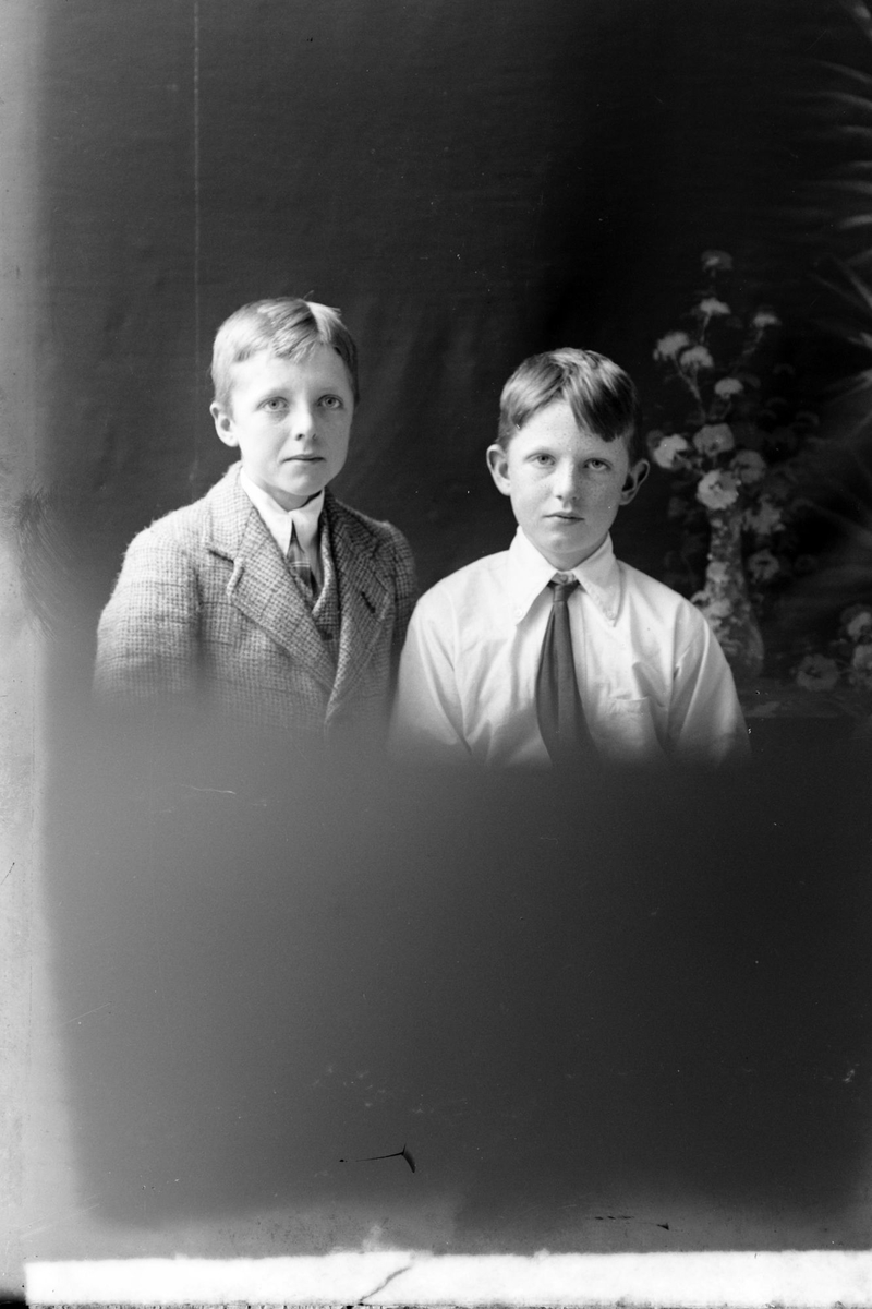 Studioportrett av to unge gutter i halvfigur.