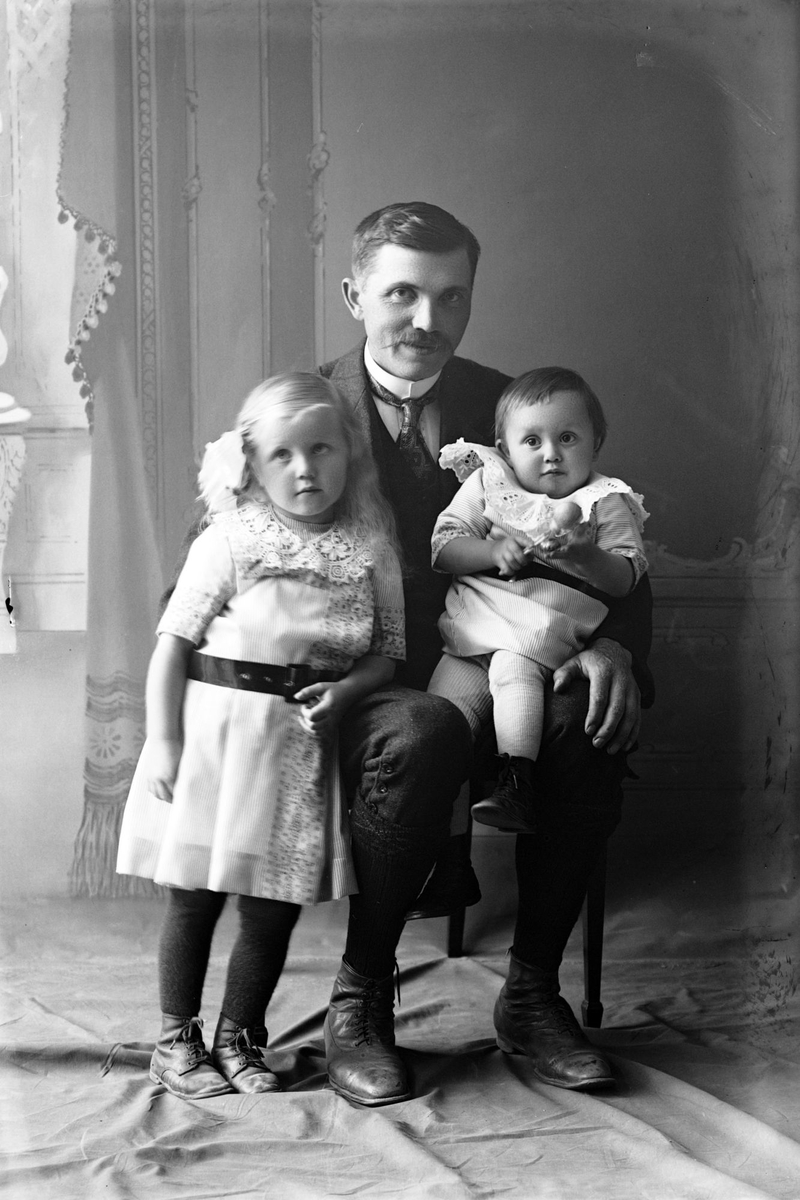 Studioportrett av en mann med to barn.