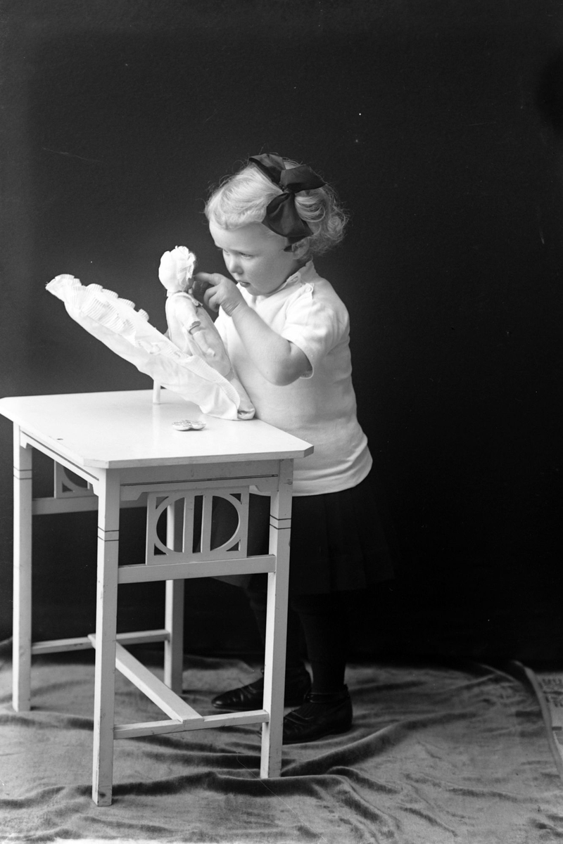 Studioportrett av en jente med en dukke.