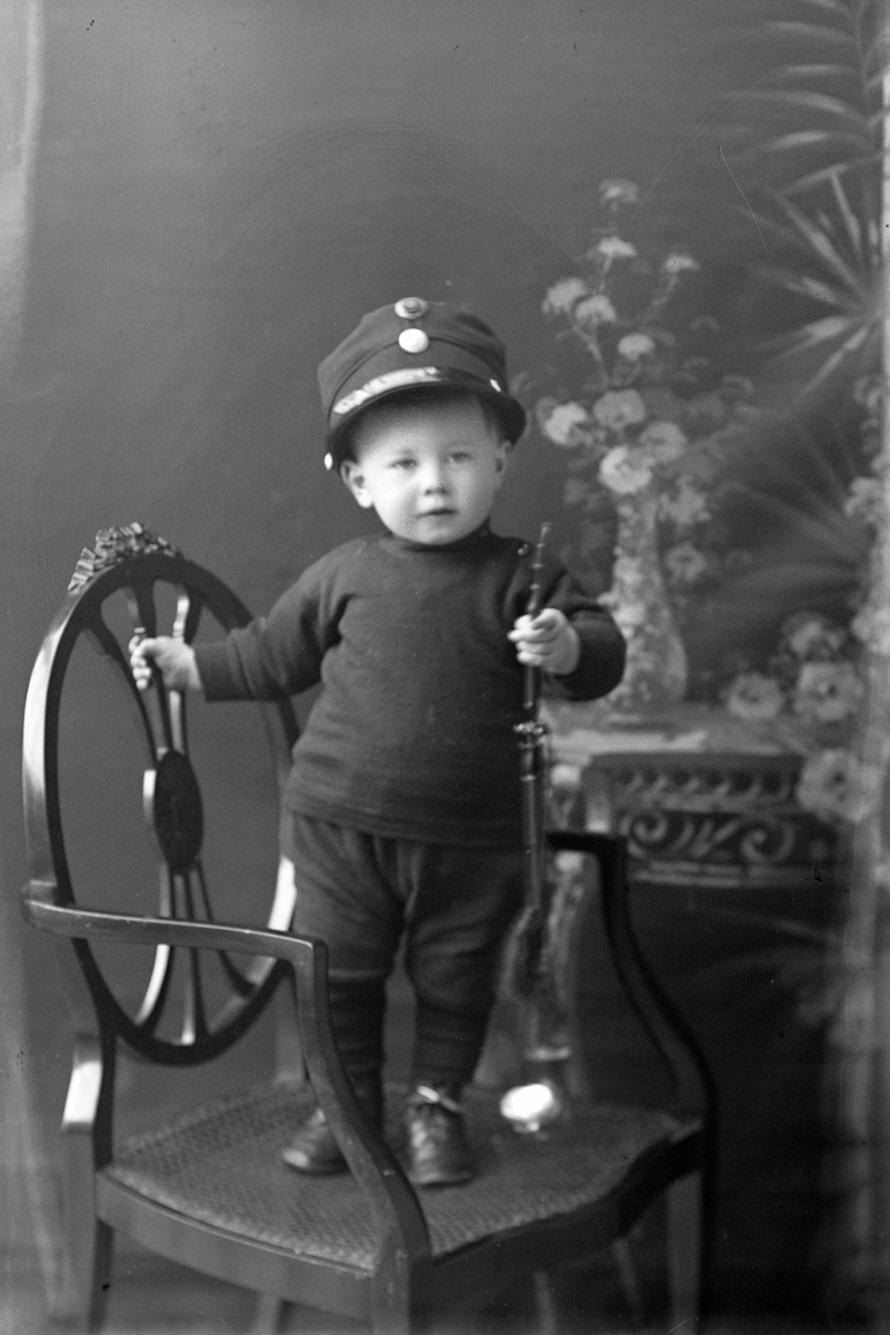 Studioportrett av en liten gutt med uniformslue.