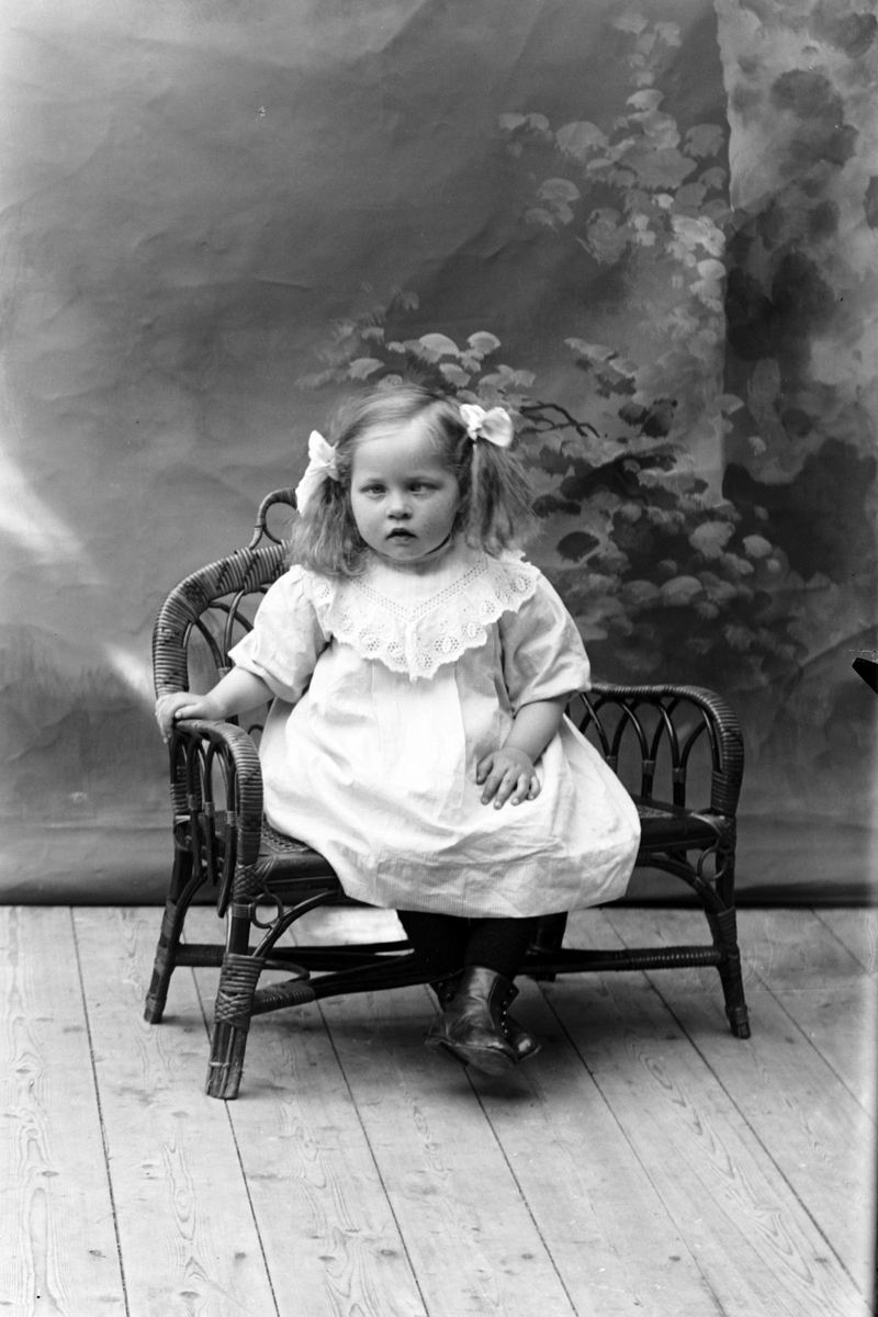 Studioportrett av en jente sittende på en stol.