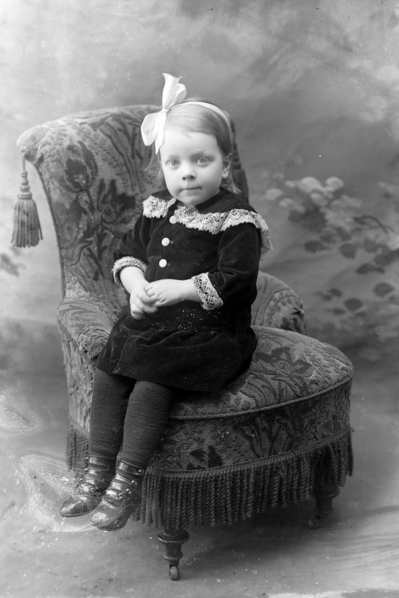 Studioportrett av en liten jente med hårbånd på hodet.