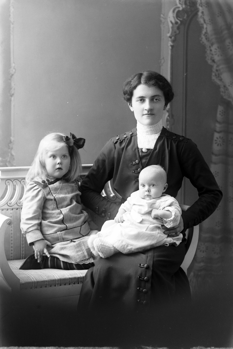 Studioportrett av en kvinne med en jente og et spedbarn.