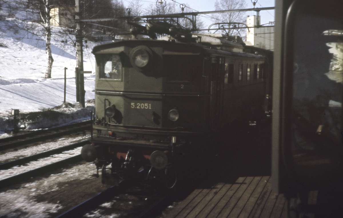 Kryssing på Eidsvoll stasjon mellom persontog retning Hamar og godstog retning Oslo, fotografert fra førerrommet på et elektrisk lokomotiv type El 13. Godstoget trekkes av elektrisk lokomotiv tye El 5.