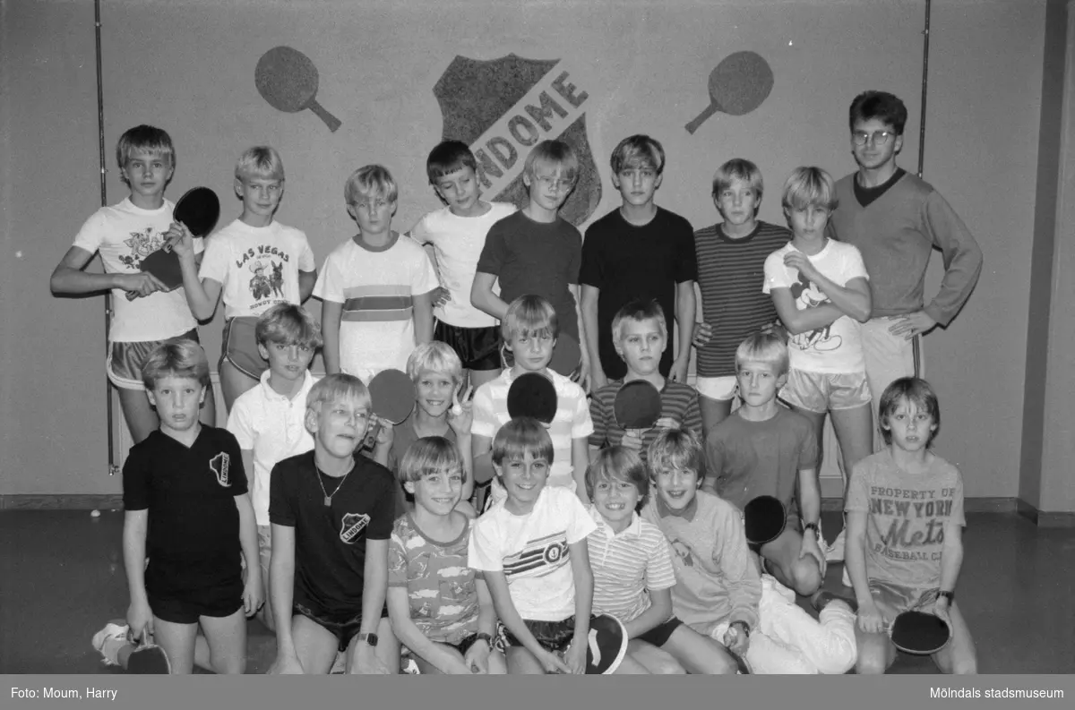 Bordtennis i Almåsskolans sporthall i Lindome, år 1984. "Tränare Roger Brundin längst till höger ser till att grabbar och flickor lär sig spelet på rätt sätt."

För mer information om bilden se under tilläggsinformation.