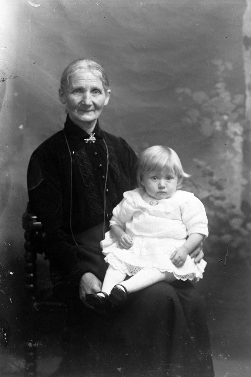 Studioportrett av en eldre kvinne med et barn på fanget.