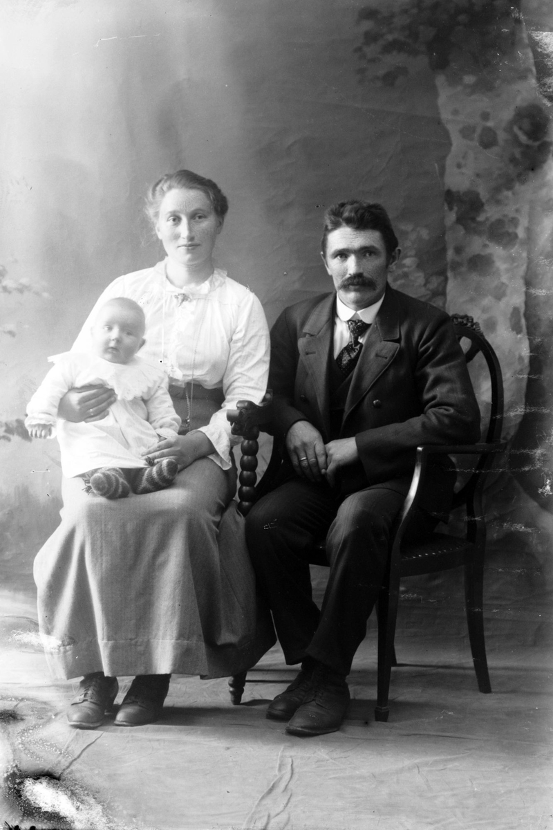Studioportrett av en mann og en kvinne med barn på fanget.