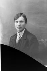 Studioportrett av en mann i halvfigur. Bildet er delvis ødel