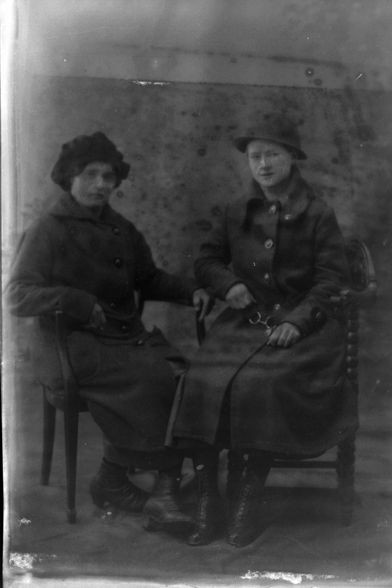 Studioportrett av to kvinner som sitter.
